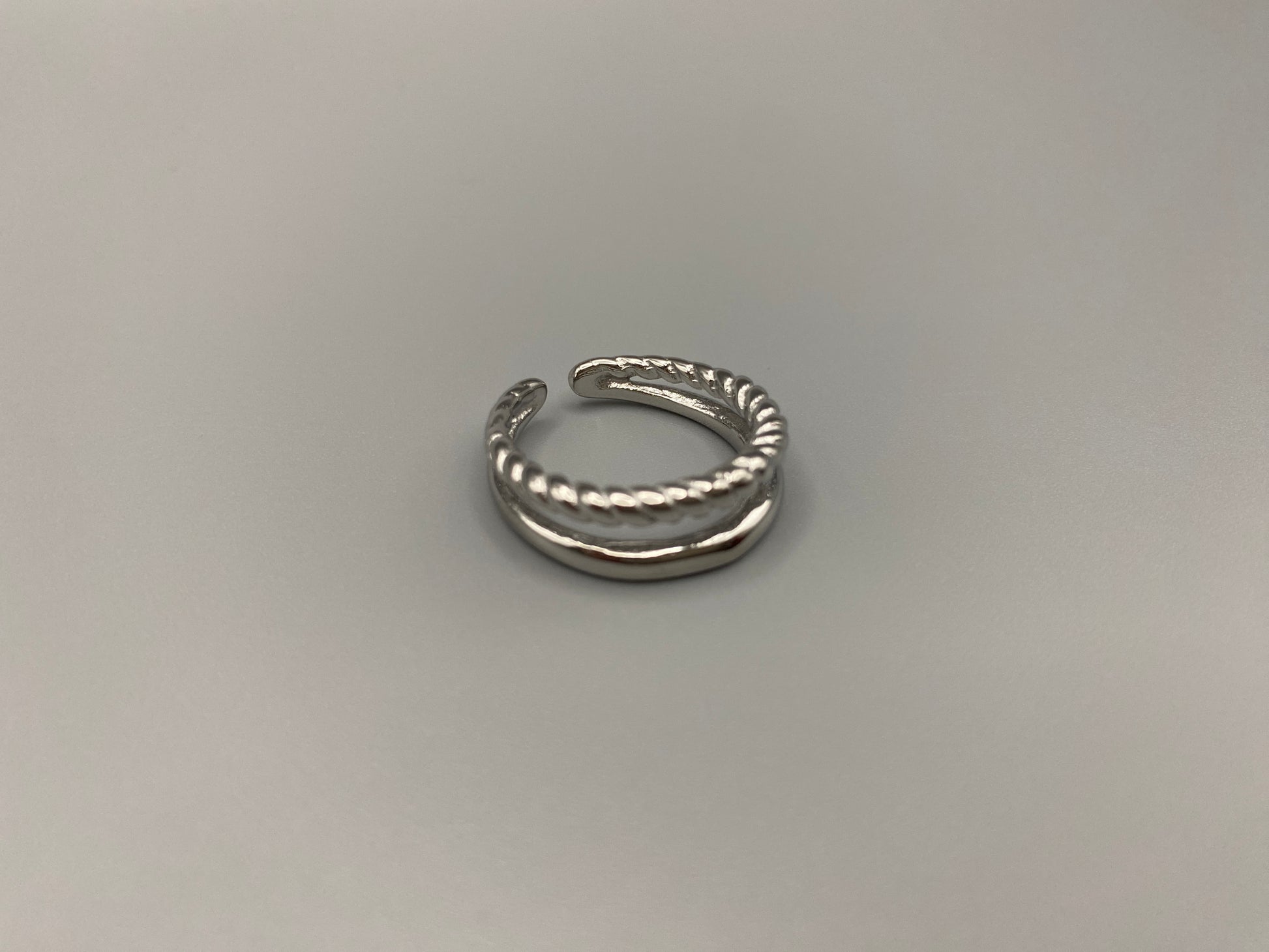 Selene Twin Band Ring Silver: This ring features a unique combination of a textured rope band and a smooth plain band, both gold plated for a luxurious finish. The titanium PVD ensures durability and resistance to wear, while the stainless steel construction adds strength and longevity. The unique twin band design combines elegance and modernity. Available in ring size 7, it is perfect for those who wear this size. Make a statement with this versatile and chic accessory that complements any look.
