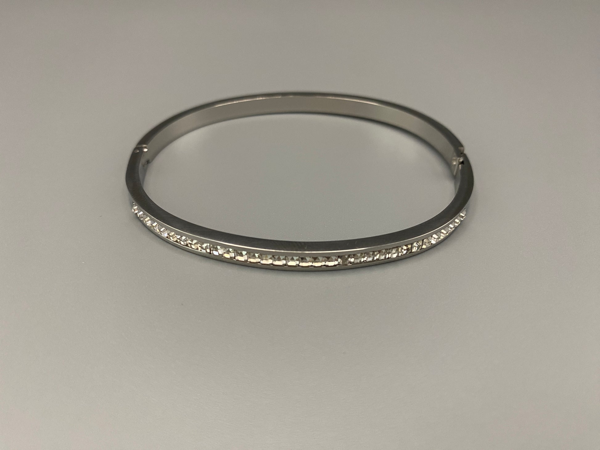 “Simone Encrusted Bangle in silver with silver plating and gemstone inlay, offering a radiant and luxurious finish. Durable construction ensures long-lasting wear and tarnish resistance. Perfect for both everyday wear and special occasions.”