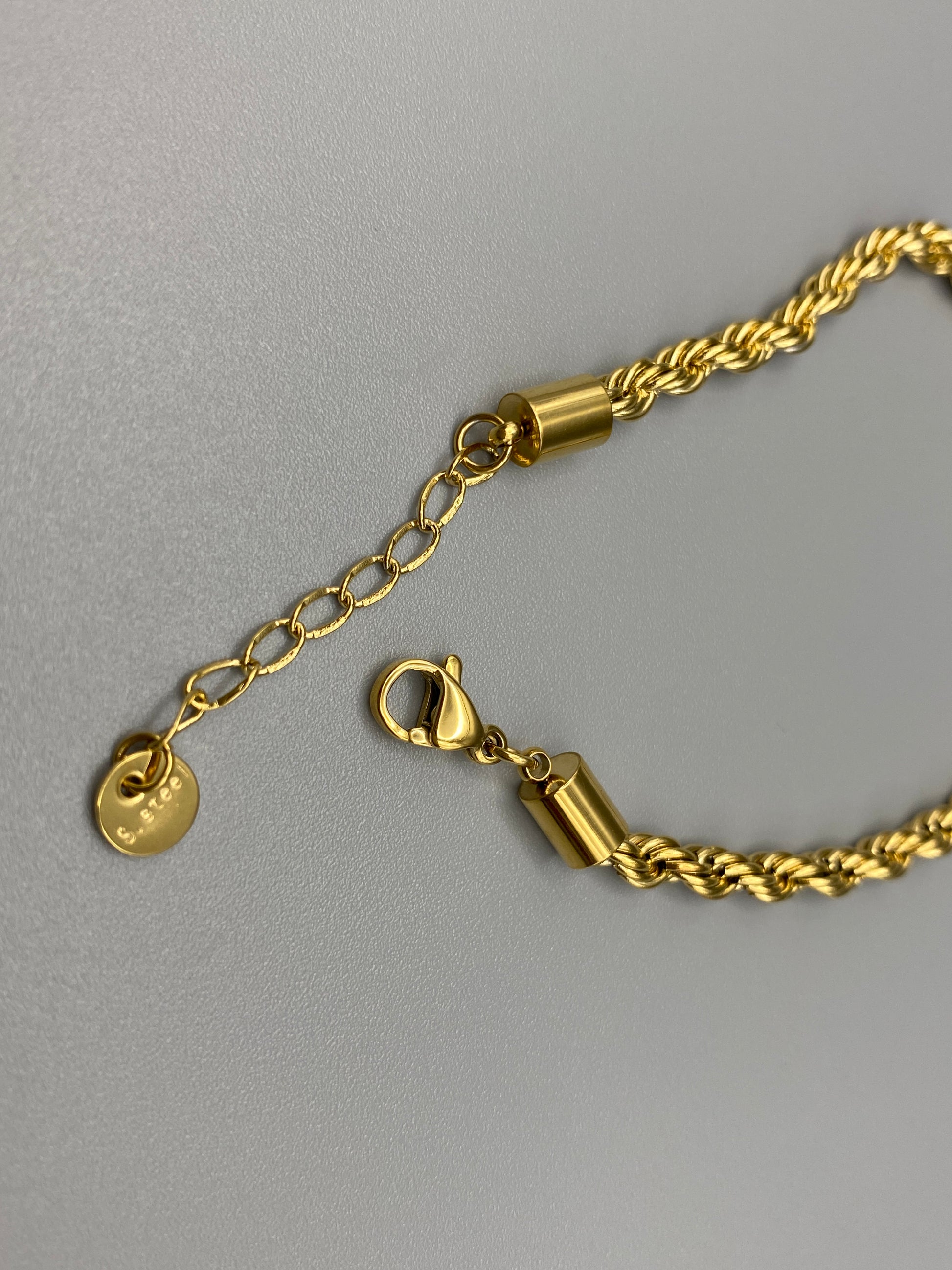 “Spiral Splendor Bracelet in gold with an intricate spiral design, featuring luxurious gold plating and PVD plating for durability. Made from stainless steel, adjustable length of 17.5 cm with a 3 cm extension.”