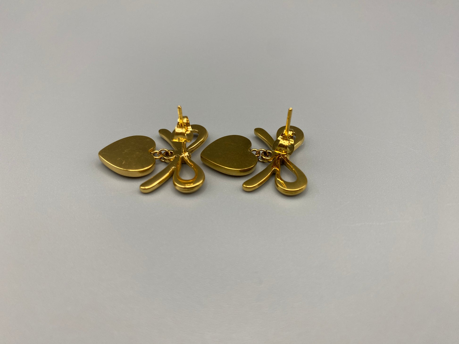 “Tanya Heart Bow Earrings Gold: Elegant and modern heart-shaped pendant adorned with a delicate bow, crafted from high-quality stainless steel and plated with 18K gold. Waterproof, tarnish-free, and environmentally friendly, perfect for daily wear or special occasions.”