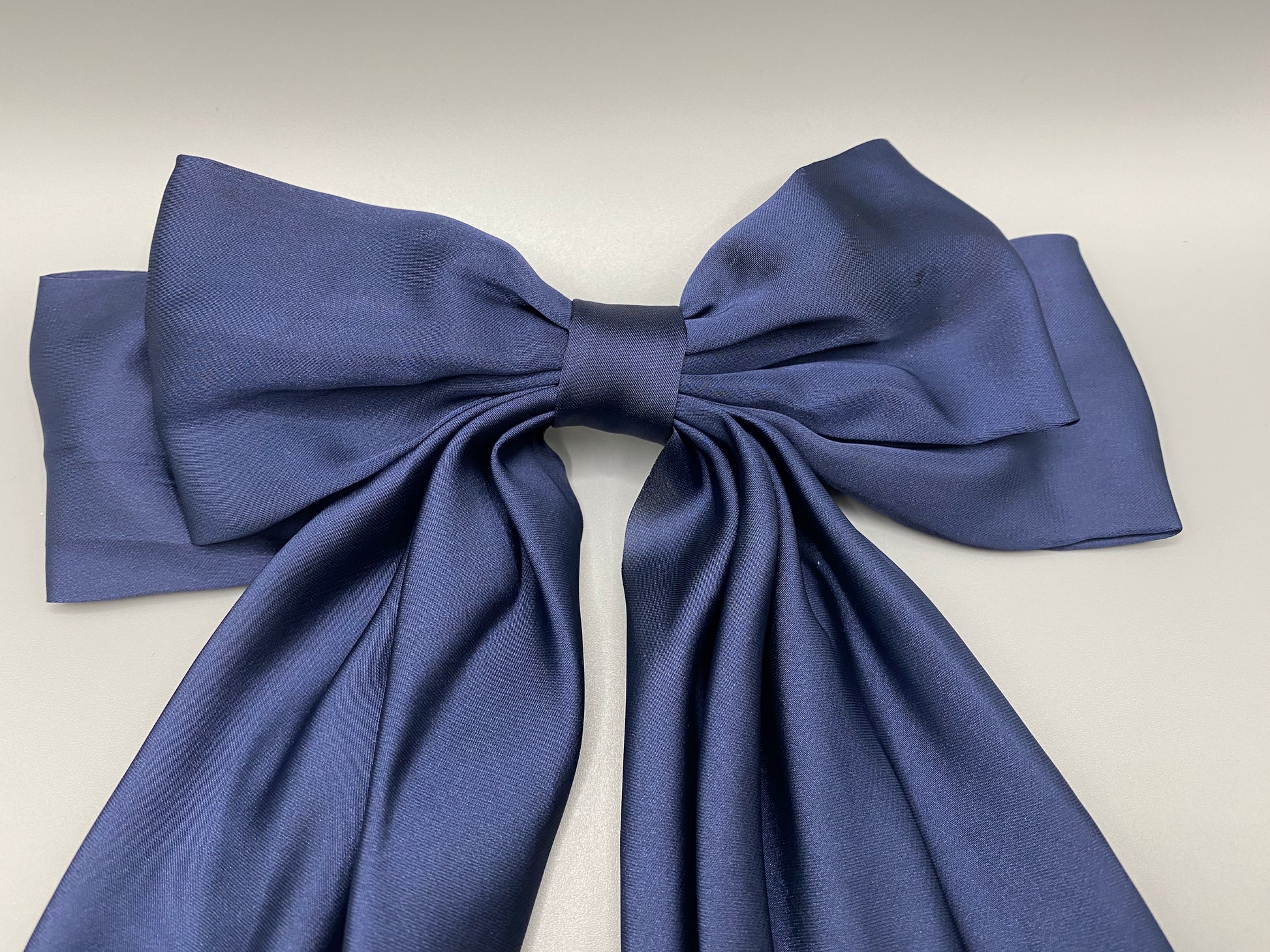 “The Amy Oversized Hair Bow in Navy Blue, crafted from high-quality satin with an oversized bowknot design. Features a minimalist spring clamp for a secure fit. Perfect for stylish updos, daily wear, and special occasions.”