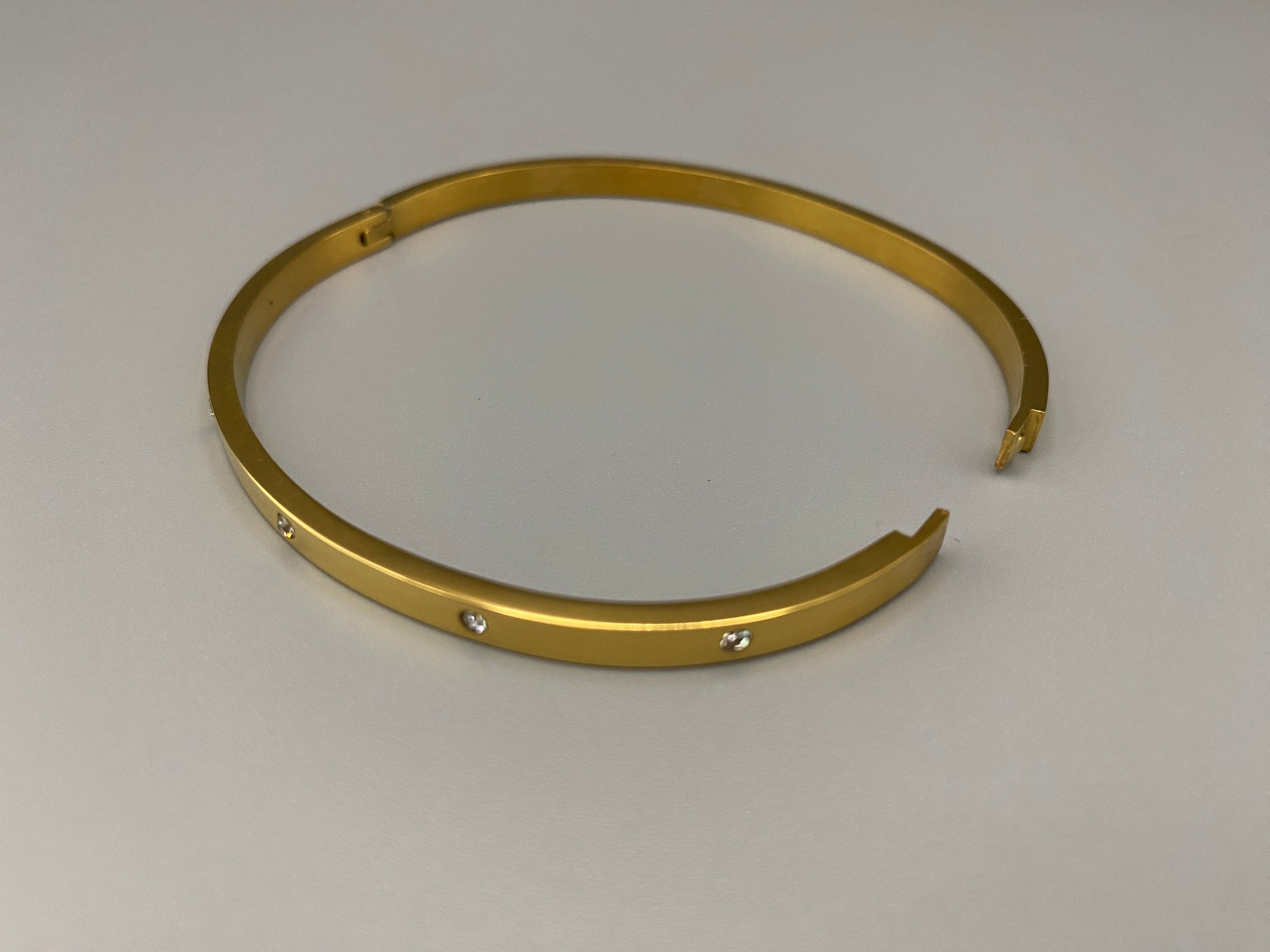 “Lucy Bangle in Gold with 18K gold plating, featuring a gemstone inlay for added elegance and sparkle. This durable bangle ensures long-lasting wear and resistance to tarnish. Its sophisticated design makes it perfect for both everyday wear and special occasions, adding a touch of glamour to any look.”