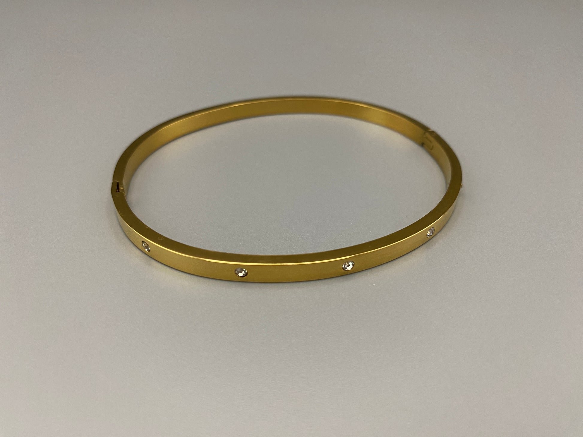 “Lucy Bangle in Gold with 18K gold plating, featuring a gemstone inlay for added elegance and sparkle. This durable bangle ensures long-lasting wear and resistance to tarnish. Its sophisticated design makes it perfect for both everyday wear and special occasions, adding a touch of glamour to any look.”