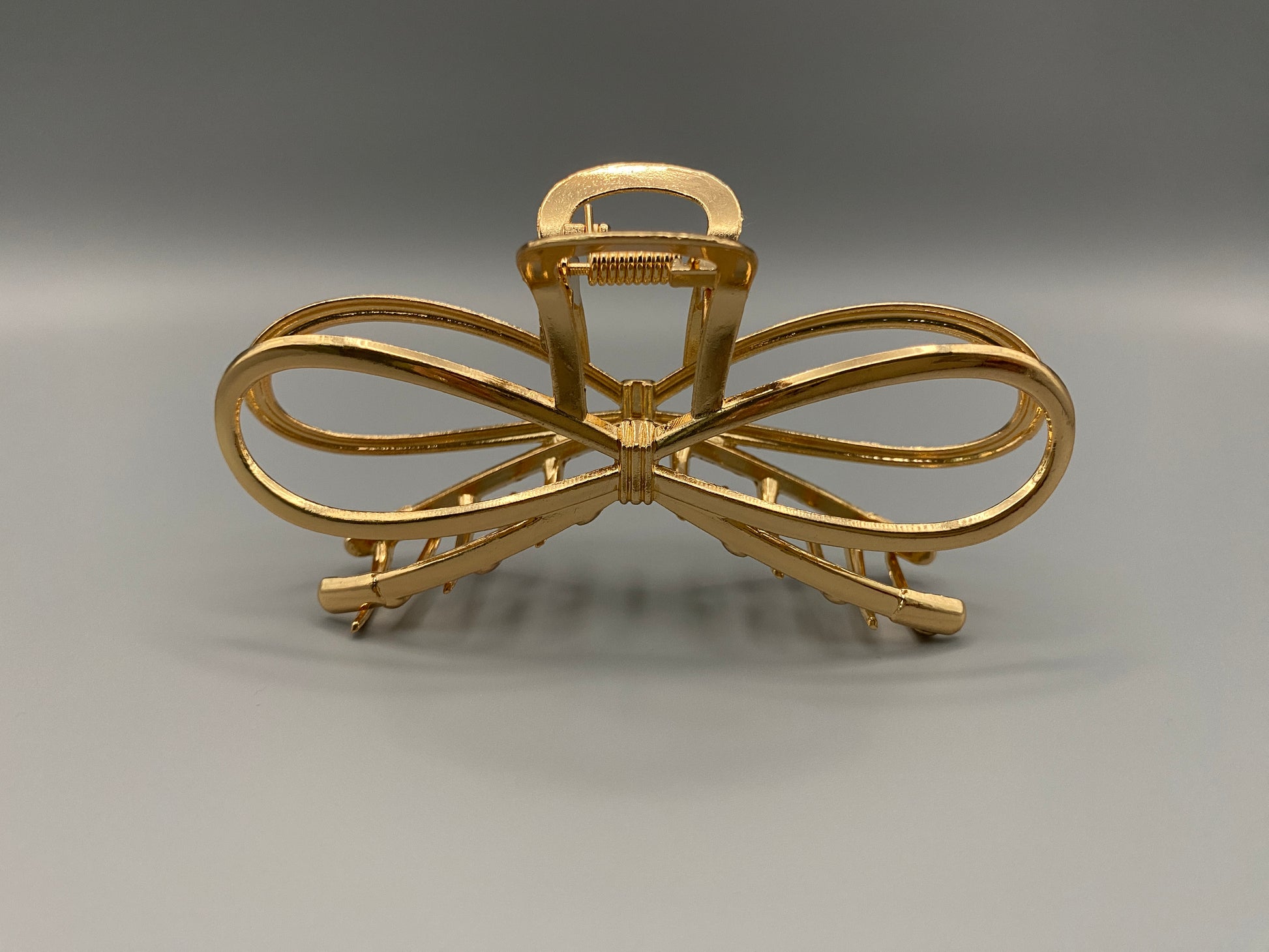 “The Luxe Claw Clip Metal Bow in Gold, crafted from high-quality, durable metal. Measures 11 cm, featuring a luxurious gold finish and unique link design. Perfect for securing various hair types and styles, suitable for both everyday wear and special occasions.”