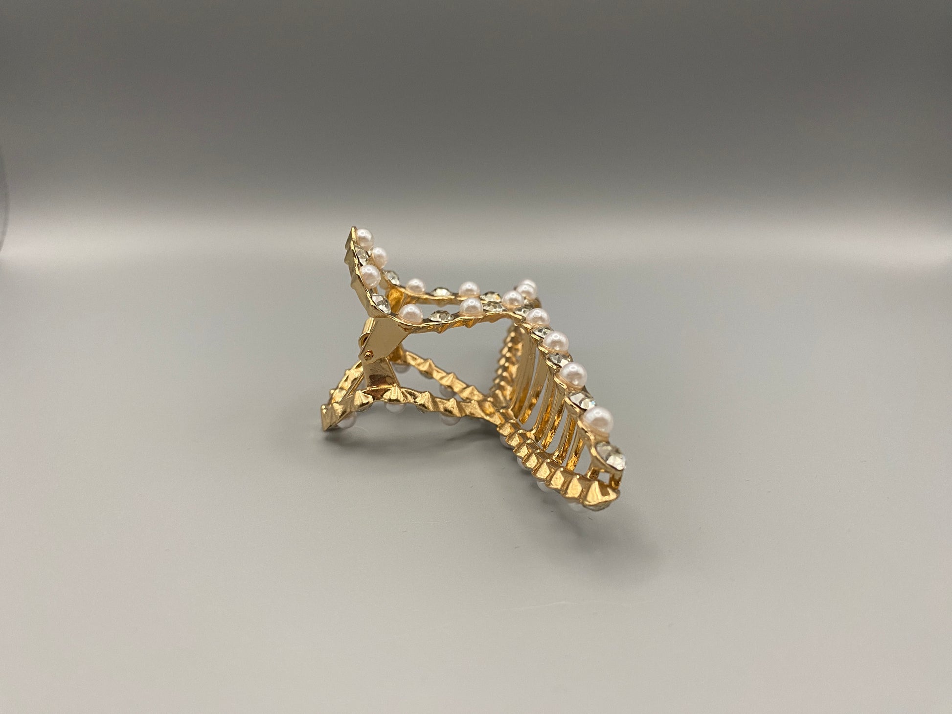 “The Luxe Claw Clip Pearl and Gem Inlay in Gold, crafted from high-quality, durable metal. Measures 11 cm, featuring a luxurious gold finish with beautiful pearl and gem accents. Perfect for securing various hair types and styles, suitable for both everyday wear and special occasions.”