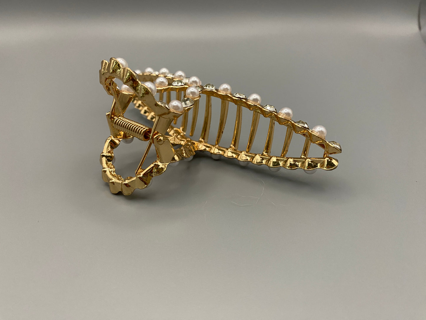 “The Luxe Claw Clip Pearl and Gem Inlay in Gold, crafted from high-quality, durable metal. Measures 11 cm, featuring a luxurious gold finish with beautiful pearl and gem accents. Perfect for securing various hair types and styles, suitable for both everyday wear and special occasions.”