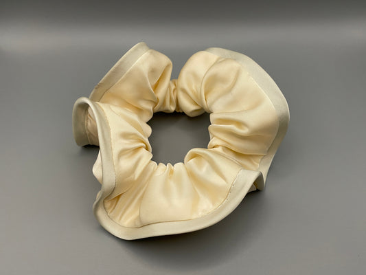 “The Rebecca Flower Scrunchie in Cream, featuring a flower-shaped design made from durable and soft satin material. Measures 11 cm, perfect for creating voluminous and eye-catching hairdos. Chic and versatile, ideal for adding a touch of vintage elegance to any outfit.”