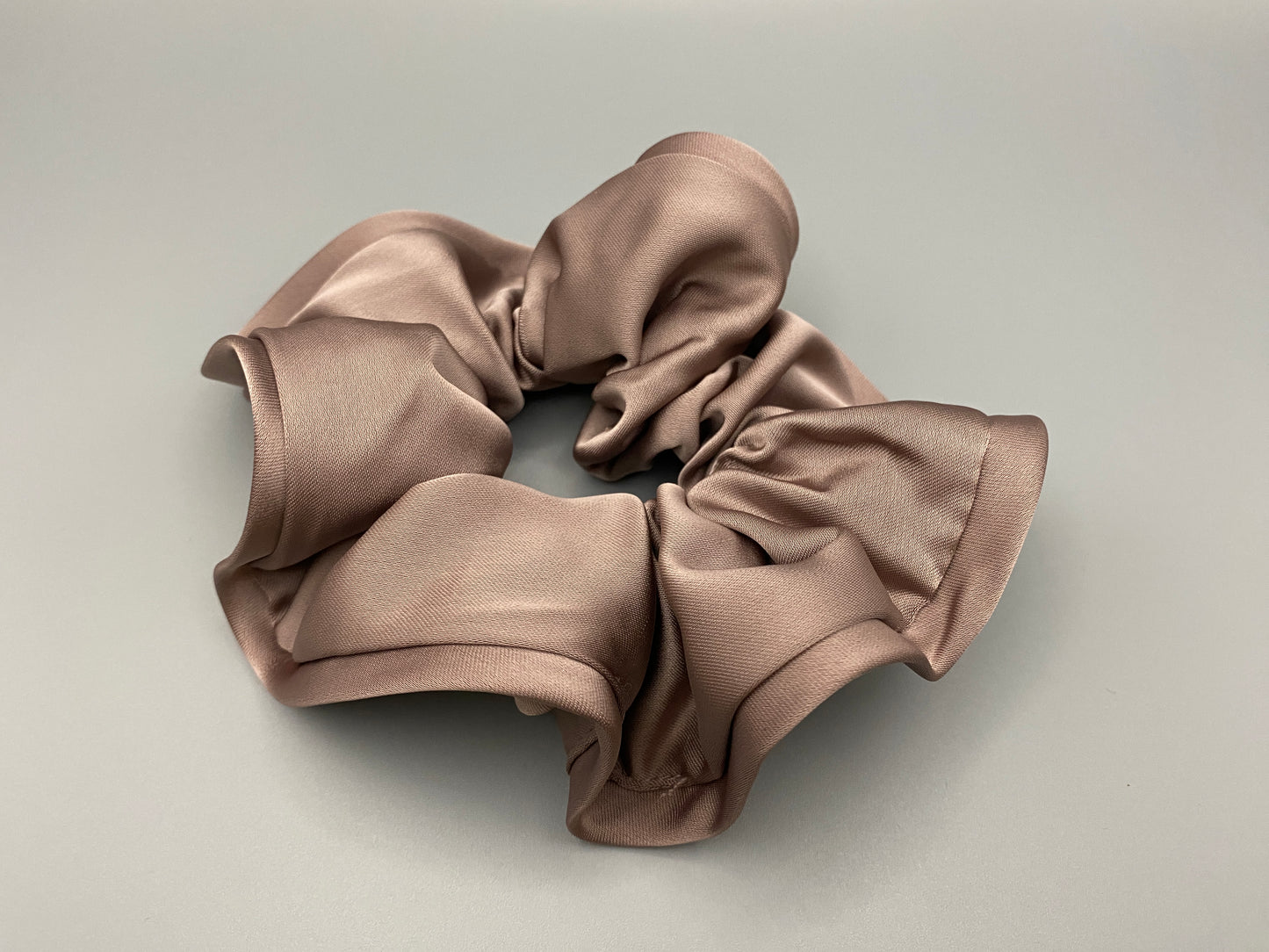 “The Rebecca Flower Scrunchie in Nude, featuring a flower-shaped design made from durable and soft satin material. Measures 11 cm, perfect for creating voluminous and eye-catching hairdos. Chic and versatile, ideal for adding a touch of vintage elegance to any outfit.”