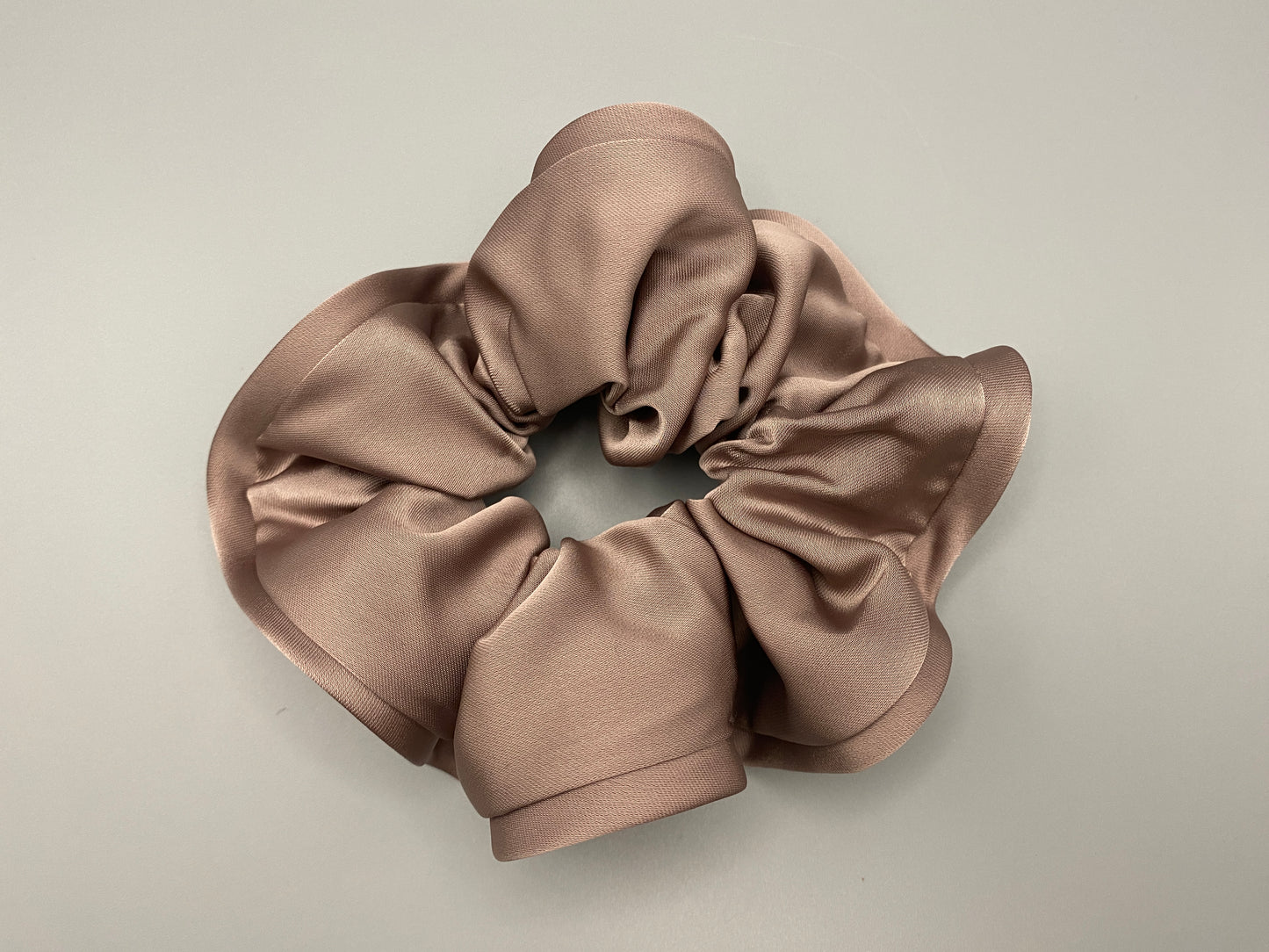 “The Rebecca Flower Scrunchie in Nude, featuring a flower-shaped design made from durable and soft satin material. Measures 11 cm, perfect for creating voluminous and eye-