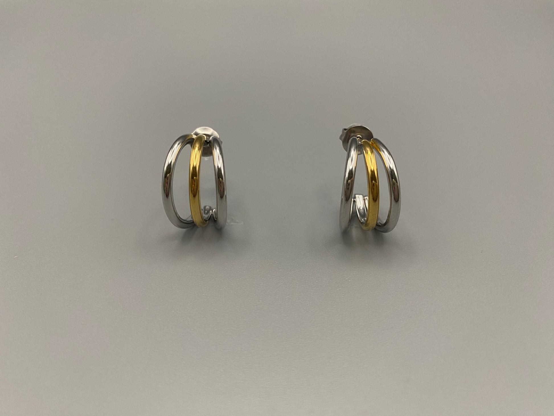 “Trinity 3 Band C Shaped Earrings Gold and Silver: A perfect blend of elegance and modern design, featuring sleek gold and silver bands, a luxurious gold-plated band, and durable stainless steel construction. Unique three-band C shape, ideal for any occasion.”