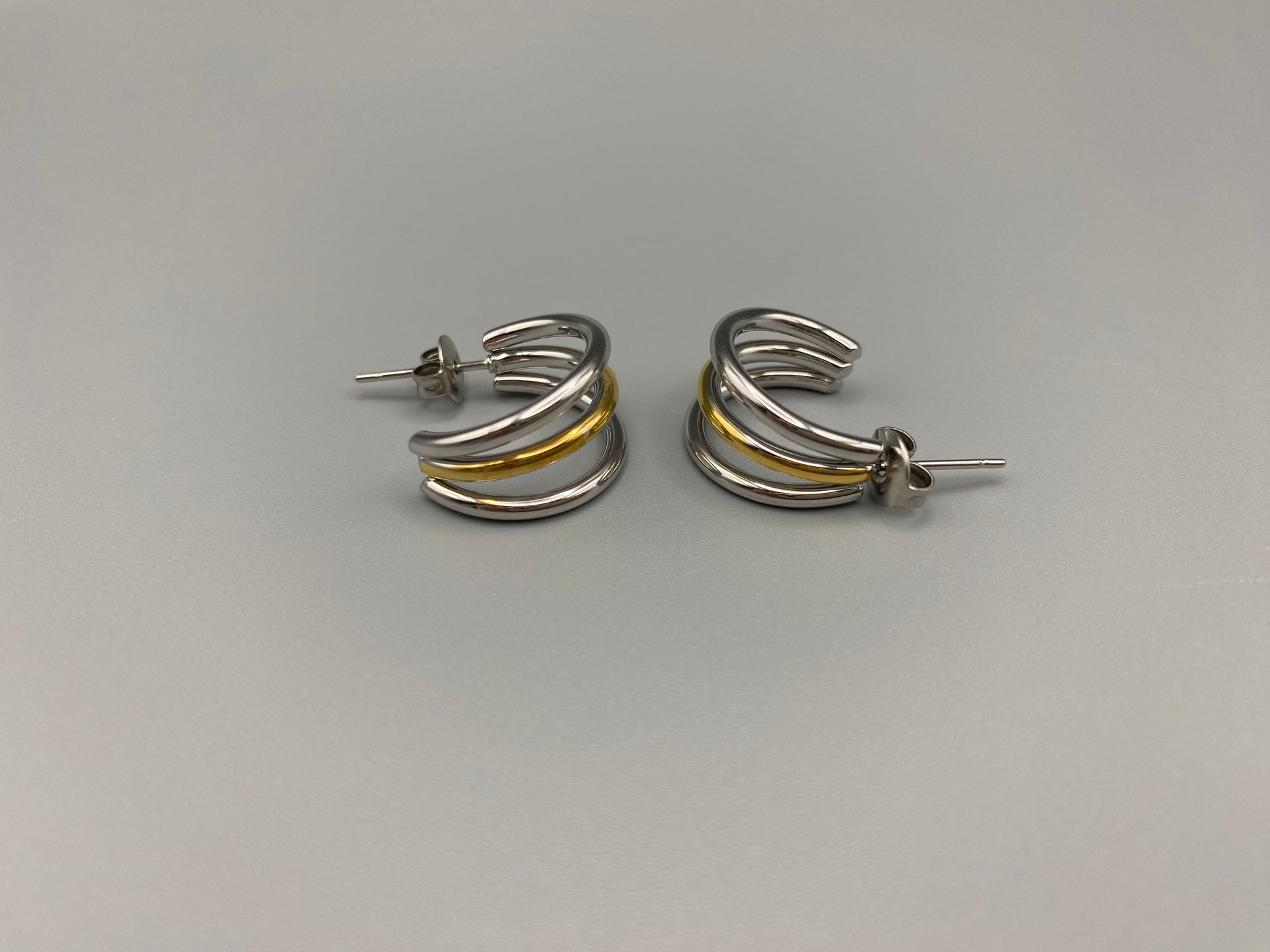 “Trinity 3 Band C Shaped Earrings Gold and Silver: A perfect blend of elegance and modern design, featuring sleek gold and silver bands, a luxurious gold-plated band, and durable stainless steel construction. Unique three-band C shape, ideal for any occasion.”