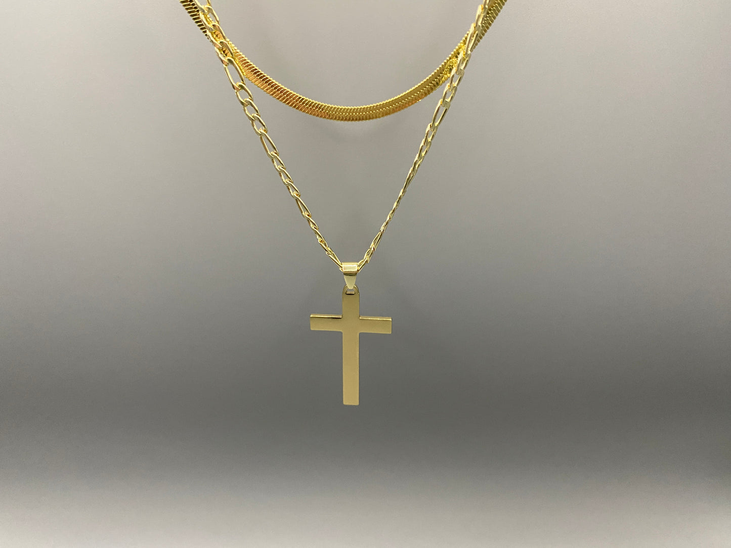 “Men’s Twin Chain Cross Necklace: A stylish 18k gold plated stainless steel necklace featuring a twin chain design with a gold cross pendant. Perfect for teens and adults, this fine jewelry piece is unisex and measures 45 cm with a 5 cm extender.”