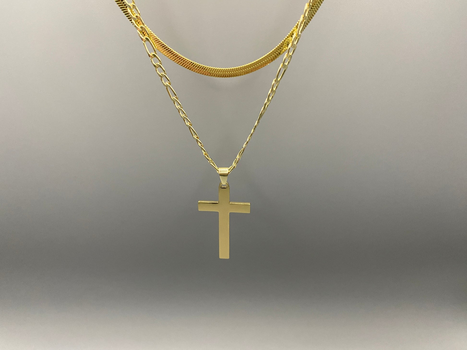 “Men’s Twin Chain Cross Necklace: A stylish 18k gold plated stainless steel necklace featuring a twin chain design with a gold cross pendant. Perfect for teens and adults, this fine jewelry piece is unisex and measures 45 cm with a 5 cm extender.”