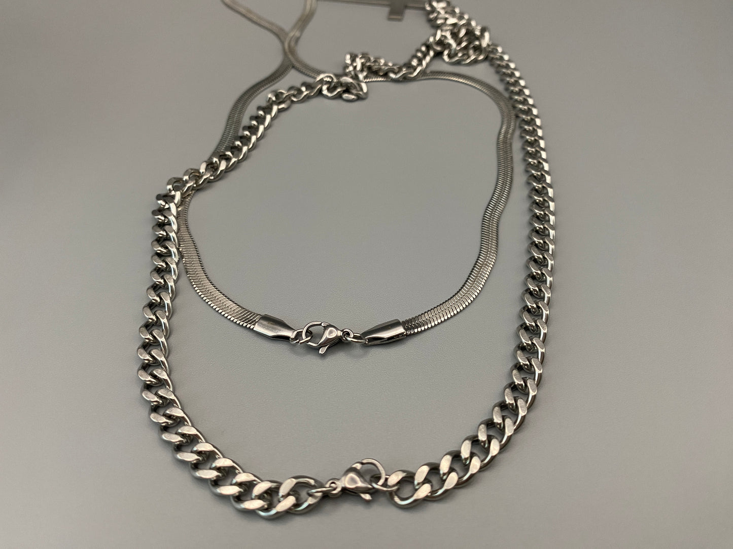 This elegant twin chain cross necklace features a striking black cross pendant, perfect for adding a touch of sophistication to any outfit. The necklace combines a thicker rope chain with a thinner snake chain, offering a unique and stylish look. Crafted from high-quality stainless steel, this piece is designed to last and maintain its shine.&nbsp;

Key Attributes:

Jewelry Main Material:&nbsp;Stainless steel
Shape/Pattern:&nbsp;Cross
Chain Length:&nbsp;Cross chain 25cm, Snake chain length 45 cm + 5 cm exte