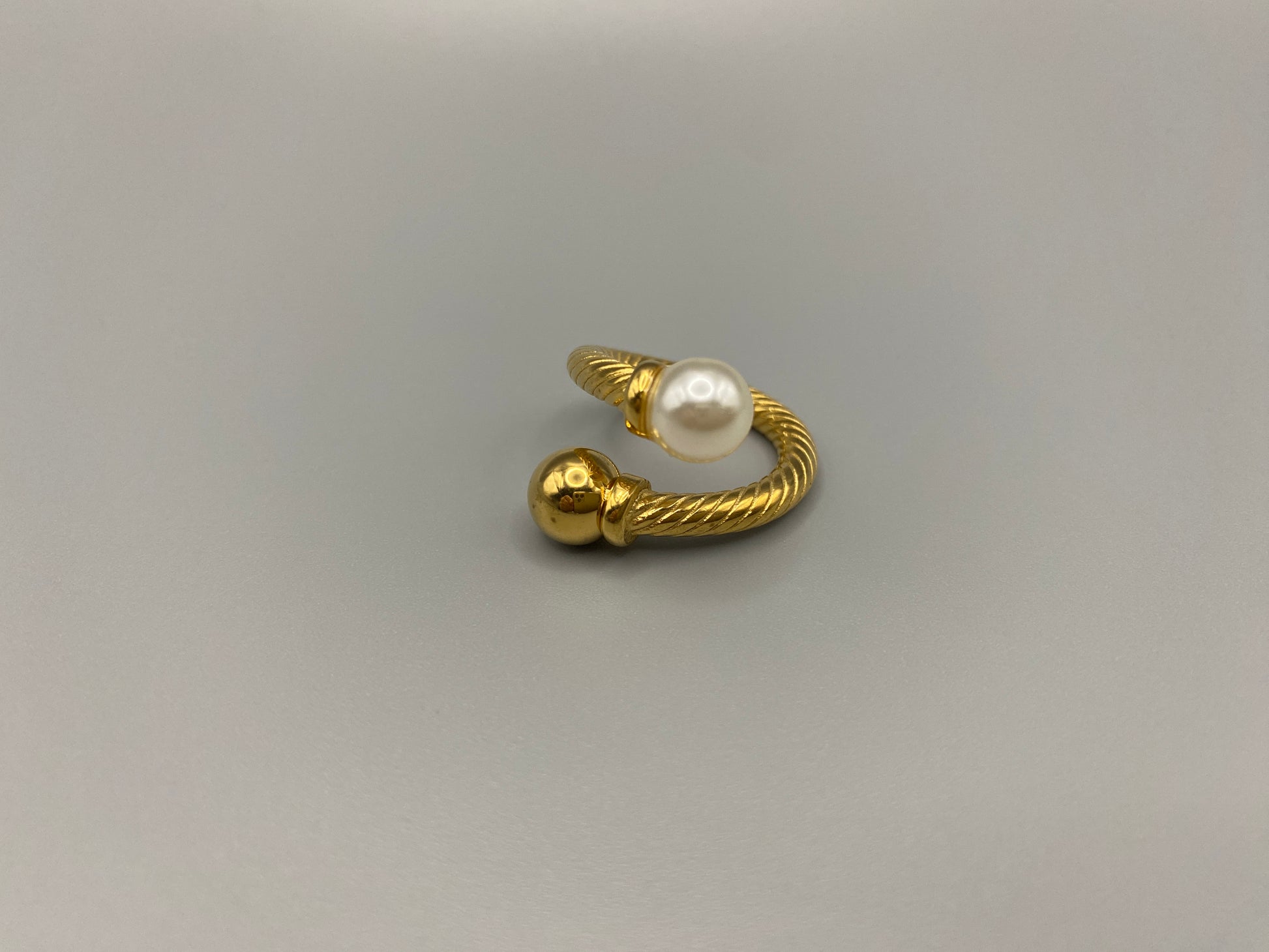 Twisted Elegance Pearl and Gold Ring: Features 18k PVD gold plating for a luxurious and durable finish. The twisted design adds a unique and elegant touch, while the pearl inlay is securely set in a claw setting. This ring is nickel-free and lead-free, making it safe for sensitive skin. It is also waterproof and non-tarnish, ensuring long-lasting beauty and wearability. Available in size 6 for a comfortable fit. Perfect for those who seek both style and substance in their jewellery.