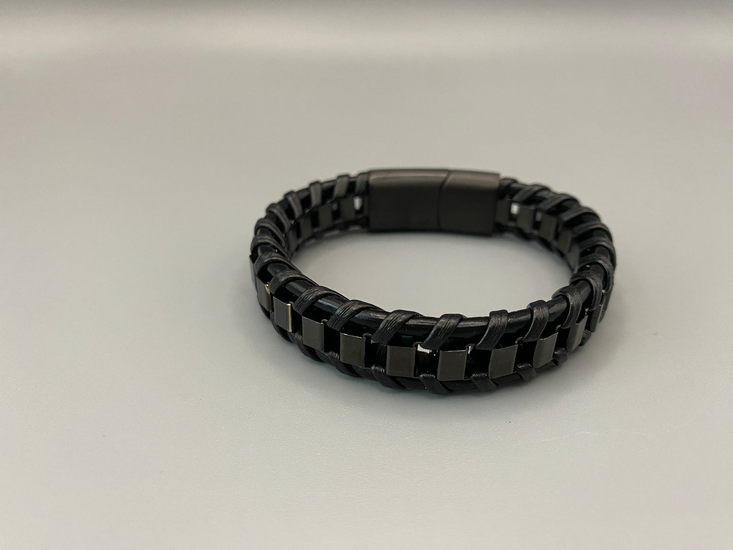 “Urban Edge Wrist Wear Men’s Bracelet in black, crafted from premium stainless steel with a casual and sporty design. Measures 19 cm in length, available in Black Zinc Plated, 18K Gold Plated, and Silver Plated finishes. Features inlay technology for added detail and craftsmanship.”