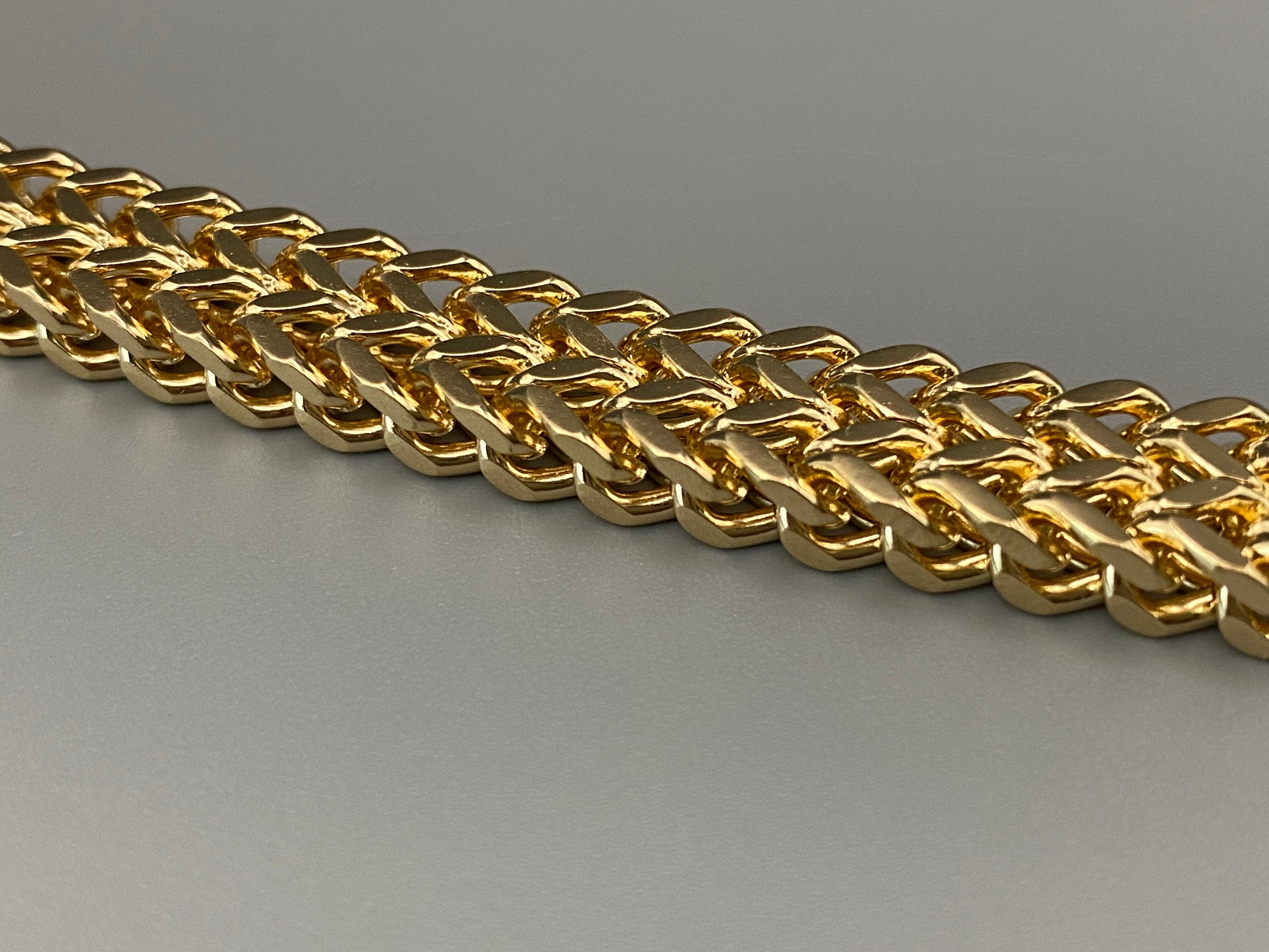 “A men’s bracelet with a chain and link design, made from shiny titanium steel. The bracelet features a geometric pattern and a smart magnet button clasp. It is available in silver, gold, and black colors, and measures 19-23 cm in length.”