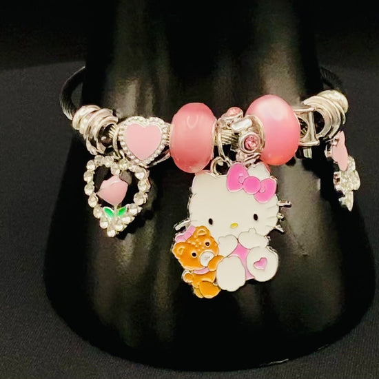 “Kitty Cartoon Character Bracelet in pink with stainless steel bangles, adorned with alloy charms, crystals, and glass beads. Features a charm with pink accents, combining playful elegance and sophistication.”