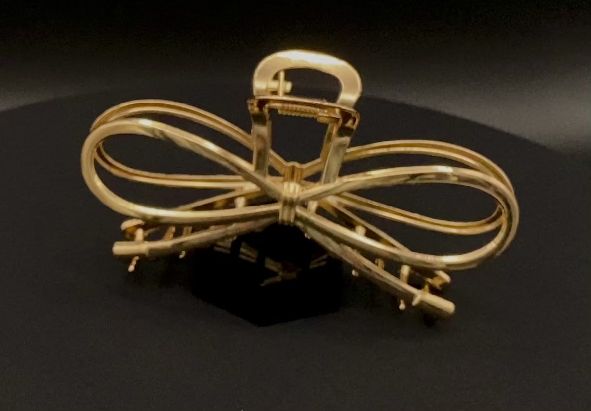 “The Luxe Claw Clip Metal Bow in Gold, crafted from high-quality, durable metal. Measures 11 cm, featuring a luxurious gold finish and unique link design. Perfect for securing various hair types and styles, suitable for both everyday wear and special occasions.”