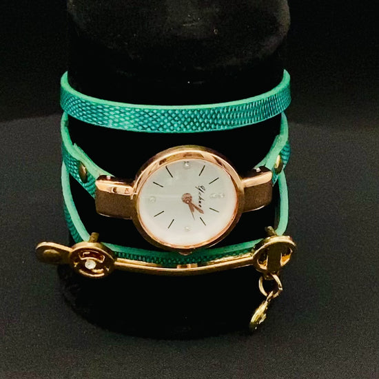 The Natasha Wristwatch Green and Gold.
A luxurious and elegant wristwatch with a black leather strap and a gold face. Features include reliable quartz movement, sparkling crystal accents on the dial, a durable 35mm alloy case, and an adjustable 24cm band with a hook buckle clasp. Note: This watch is not waterproof. Perfect for adding a touch of charm, fashion, and luxury to any outfit.