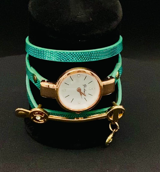 The Natasha Wristwatch Green and Gold.
A luxurious and elegant wristwatch with a black leather strap and a gold face. Features include reliable quartz movement, sparkling crystal accents on the dial, a durable 35mm alloy case, and an adjustable 24cm band with a hook buckle clasp. Note: This watch is not waterproof. Perfect for adding a touch of charm, fashion, and luxury to any outfit.