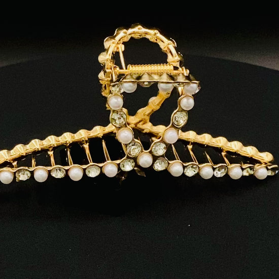 “The Luxe Claw Clip Pearl and Gem Inlay in Gold, crafted from high-quality, durable metal. Measures 11 cm, featuring a luxurious gold finish with beautiful pearl and gem accents. Perfect for securing various hair types and styles, suitable for both everyday wear and special occasions.”
