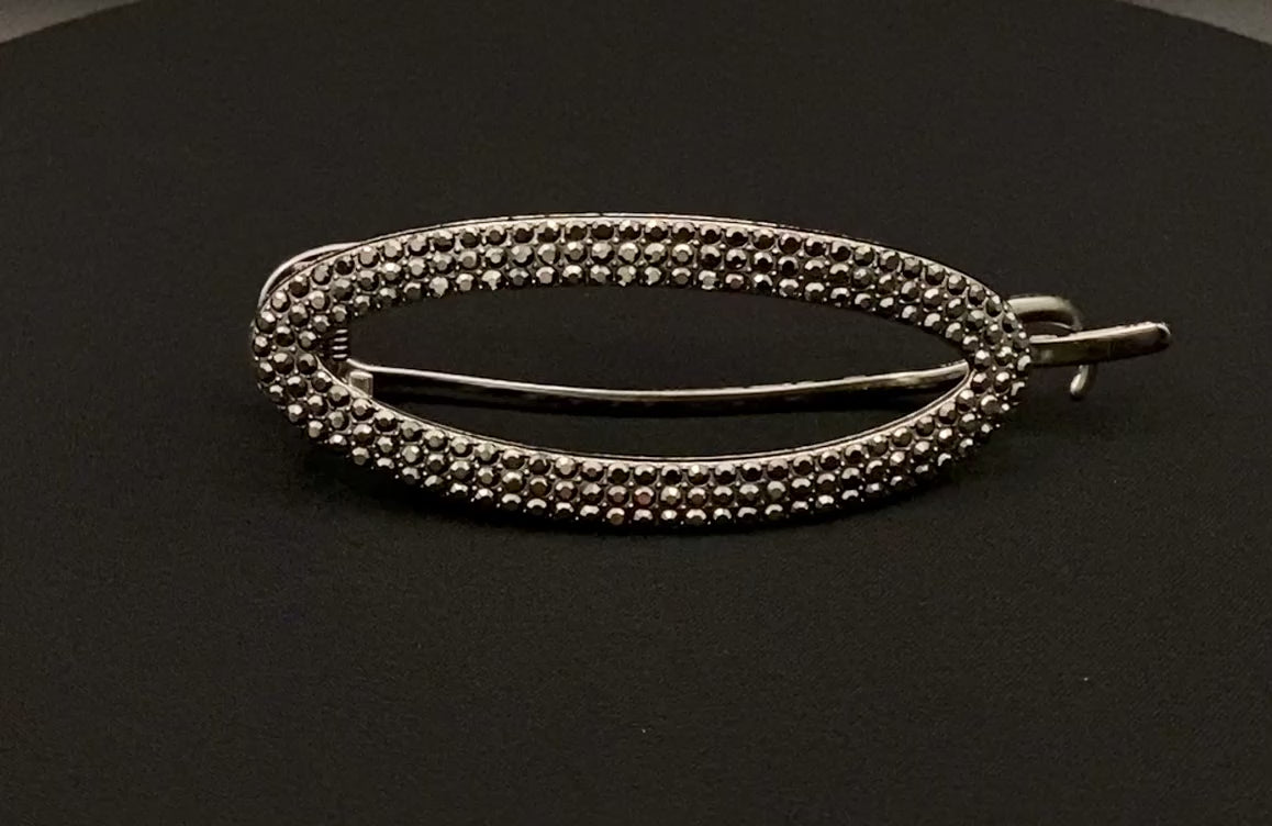 “GlitzGrip Oval Hollow Silver Hair Clip with a hollow oval design, encrusted with sparkling zircon gems. Measures 9.5 cm in length, offering a secure hold for various hair types and styles. Elegant and durable, perfect for both casual and formal hairstyles.”