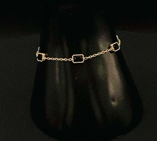 “Clarissa Bracelet in gold with black zircon inset stones, featuring a luxurious gold plating and adjustable length of 17.5 cm with a 2 cm extension. Durable construction ensures long-lasting wear and tarnish resistance.”