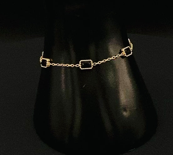 “Clarissa Bracelet in gold with black zircon inset stones, featuring a luxurious gold plating and adjustable length of 17.5 cm with a 2 cm extension. Durable construction ensures long-lasting wear and tarnish resistance.”