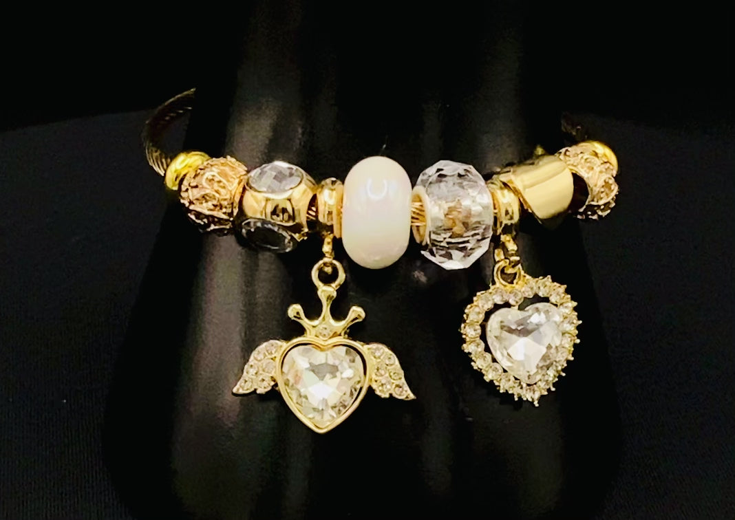 “Belle White Charm Bracelet with gold-plated finish, featuring heart-cut crystals and rhinestones. Made from durable stainless steel with playful charms and micro insert inlay technology.”
