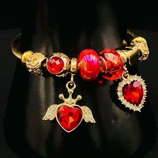 “Belle Red Charm Bracelet with gold-plated finish, featuring heart-cut crystals and rhinestones. Made from durable stainless steel with playful charms and micro insert inlay technology.”