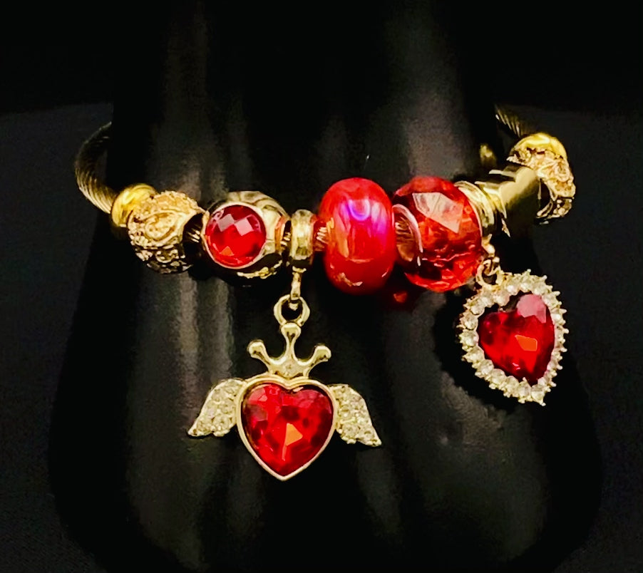 “Belle Red Charm Bracelet with gold-plated finish, featuring heart-cut crystals and rhinestones. Made from durable stainless steel with playful charms and micro insert inlay technology.”